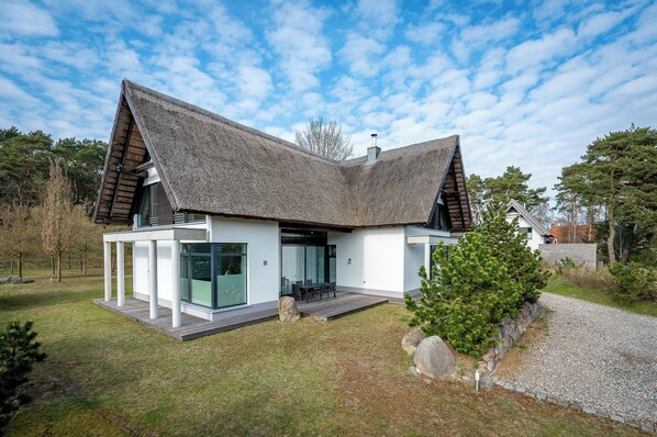 Una casa moderna con techo inclinado, ventanas amplias y un césped bien cuidado.