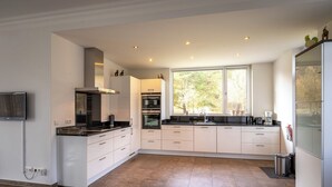 Una cocina moderna con armarios blancos, horno empotrado y un amplio ventanal que ofrece luz natural.
