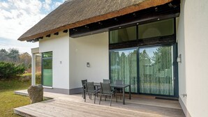 Una casa moderna con un patio, una mesa de comedor con sillas y un gran ventanal.