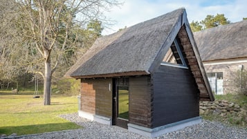 Eine kleine Holzhütte mit einem Strohdach, einer Tür und einem Fenster.