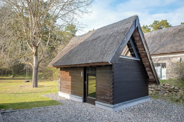 Eine kleine Holzhütte mit einem Strohdach, einer Tür und einem Fenster.