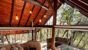 A wooden interior with a hot tub, a sofa, and large windows.