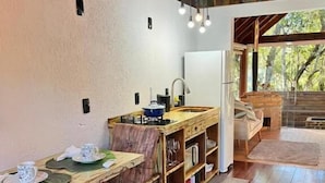 A rustic kitchen with wooden furniture, a dining table set, and a view of the outdoors.