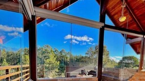 A hot tub with rose petals and a bottle of wine, surrounded by a wooden deck and a view of trees.
