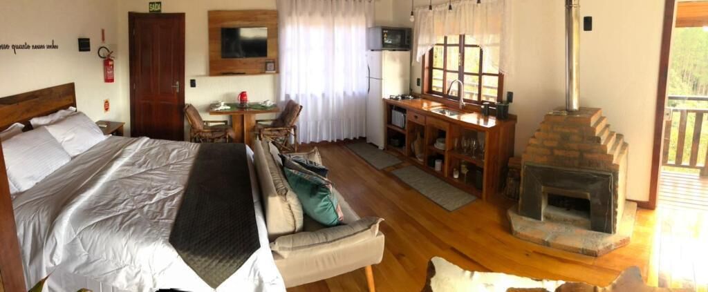 A bedroom with a bed, a sofa, a desk, a fireplace, and a window.
