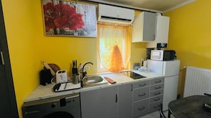 A compact kitchen with a sink, a toaster, a microwave, and a window with curtains.