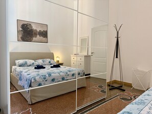 Un dormitorio con cama, mesita de noche, lámpara, armario y espejo.