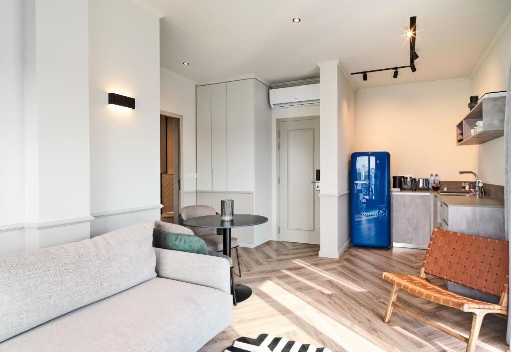 Una sala de estar moderna con un sofá, una mesa de comedor y una zona de cocina con refrigerador.