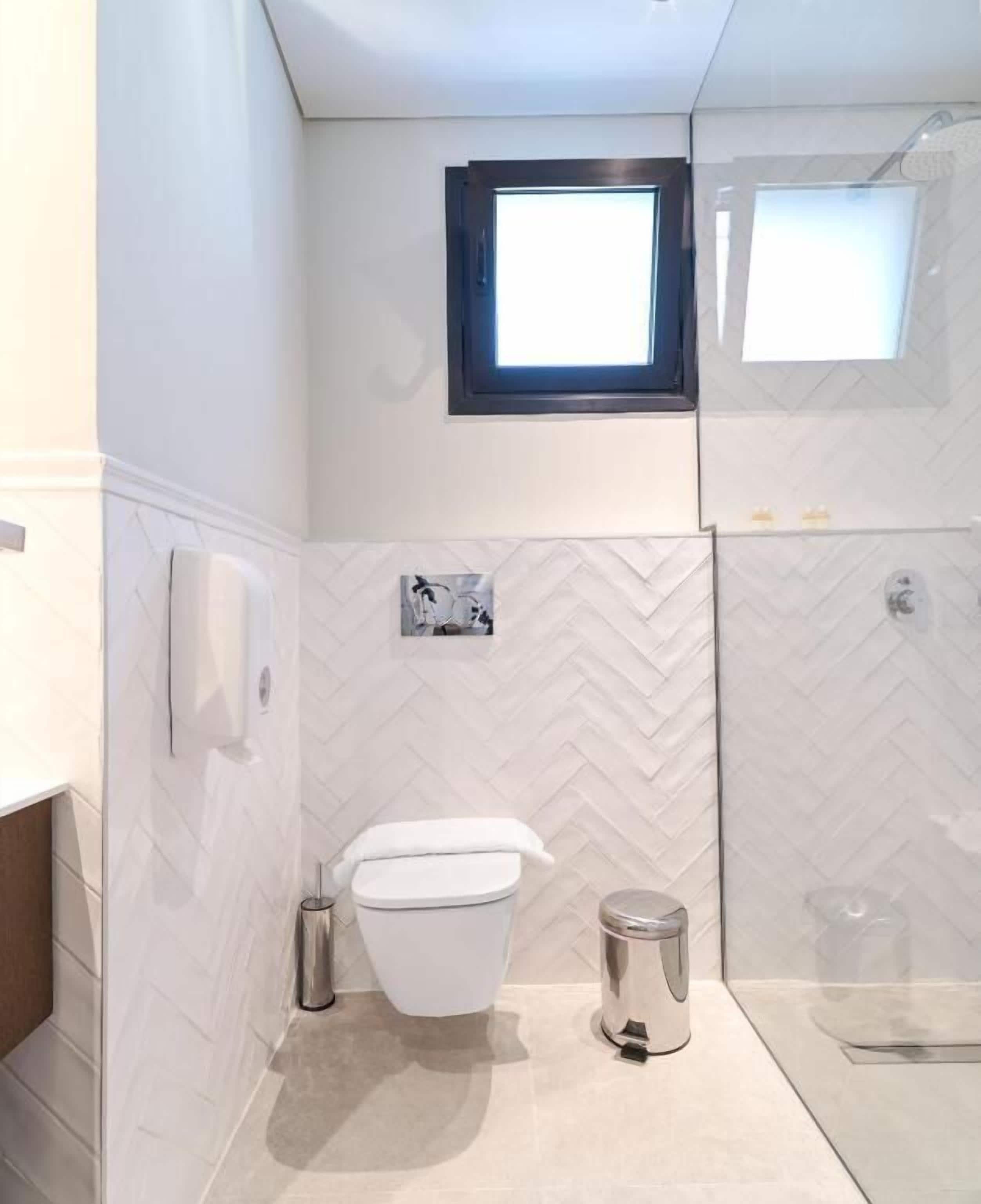 A bathroom with a white toilet, a trash can, and a shower area.