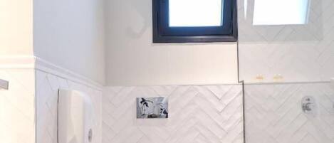A bathroom with a white toilet, a trash can, and a shower area.
