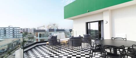 Una terraza en la azotea con suelo a cuadros, mobiliario exterior y vistas a la ciudad.