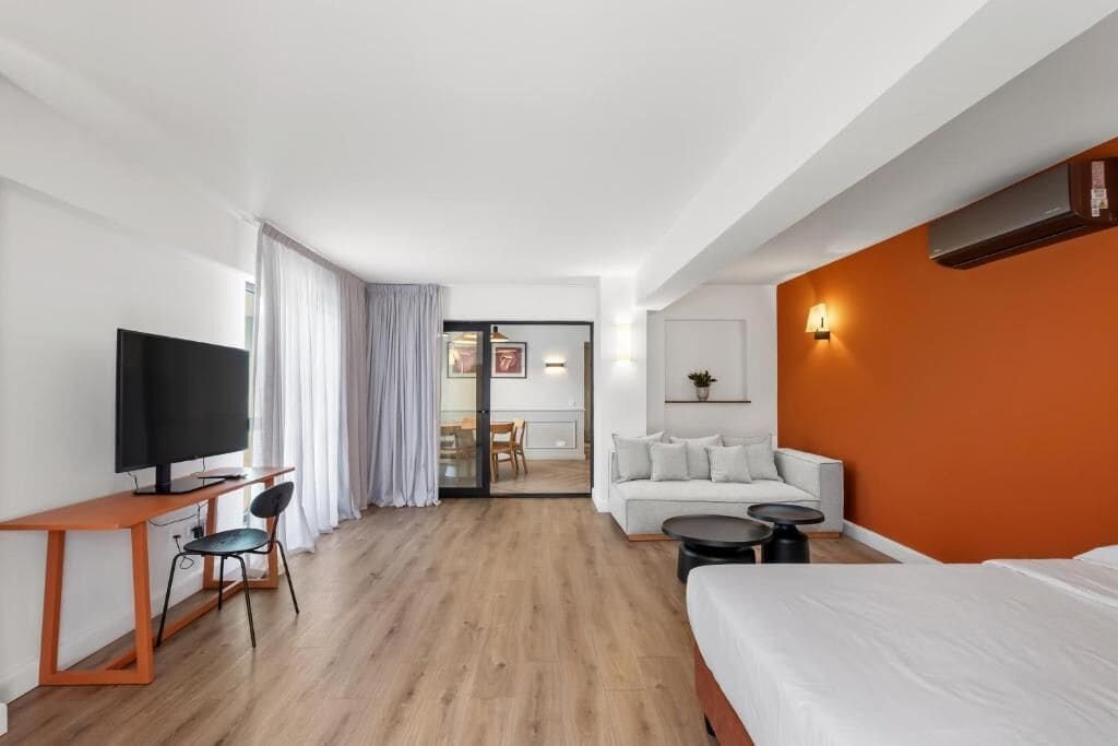 Een moderne hotelkamer met een televisie, een bureau, een sofa en een bed.