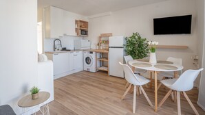 Une cuisine moderne avec des meubles blancs, un four à micro-ondes, un lave-linge et un coin repas comprenant une table et des chaises.