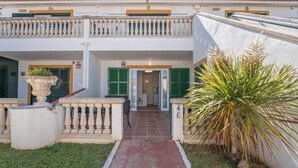 Un bâtiment doté d’une entrée couverte, d’un petit jardin avec un palmier et d’un balcon agrémenté de balustrades.