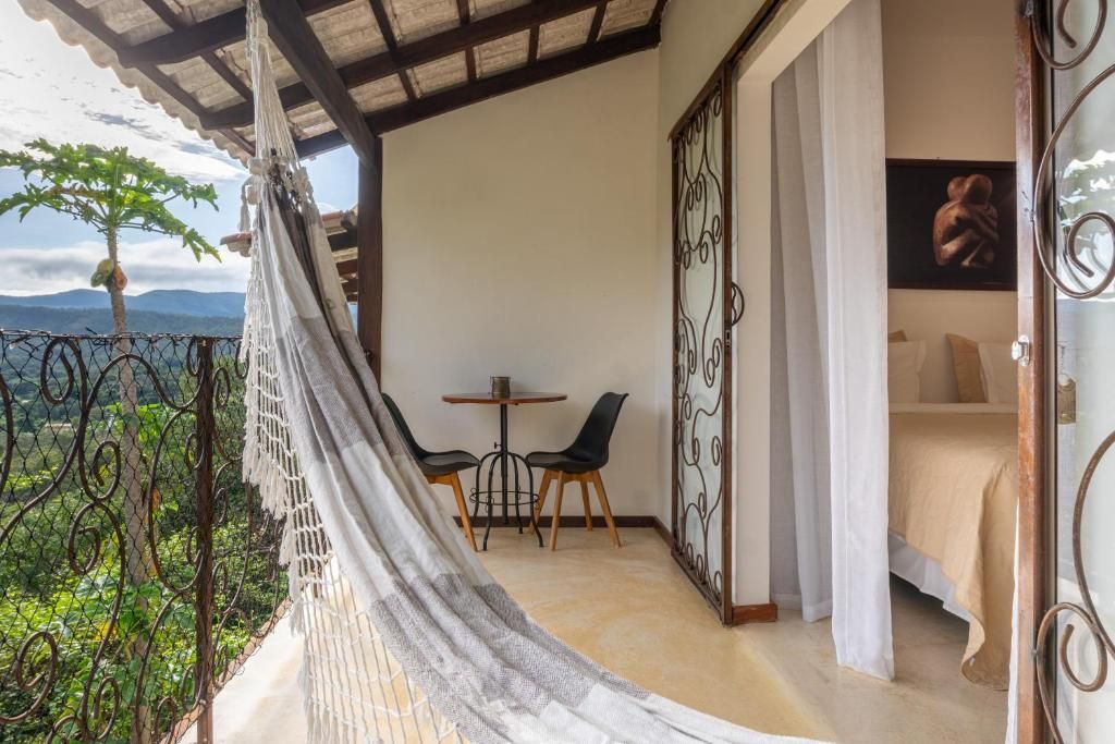 Un balcon avec un hamac, une petite table avec des chaises et un lit recouvert d’une courtepointe blanche.