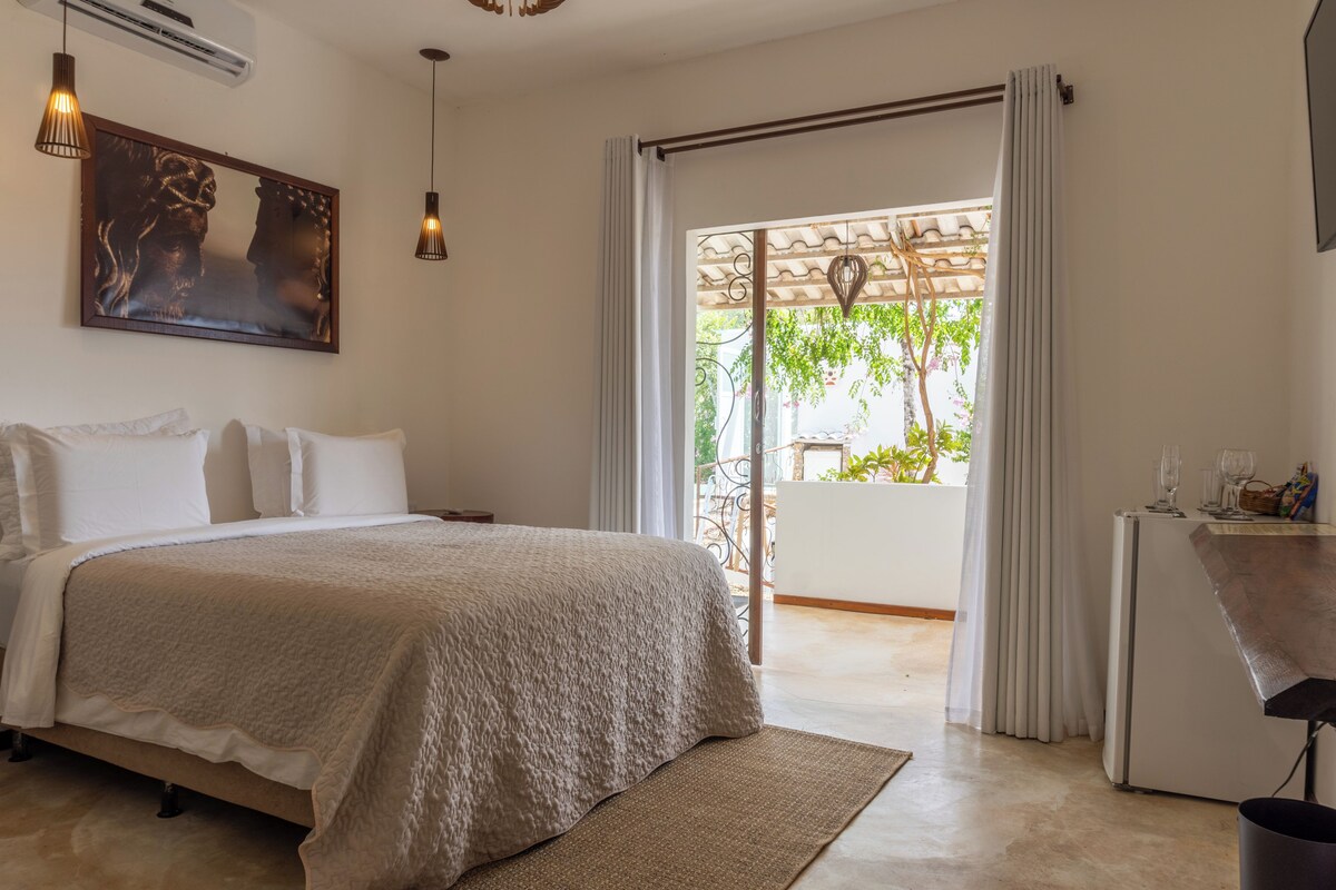 A bedroom with a bed, a desk, a chair, a window, and a door.