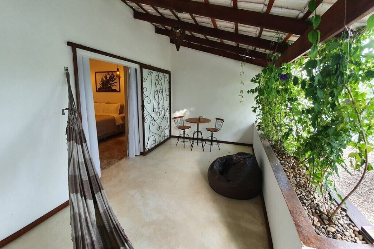 A room with a hammock, a small table with chairs, a bean bag, and a planter with greenery.