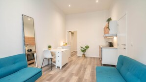 Un espacio habitable compacto con kitchenette, zona de comedor y área de estar con dos sofás.