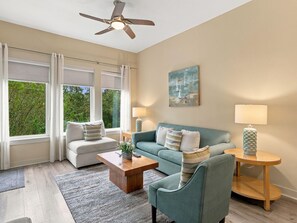 Ein Wohnzimmer mit Sofa, Sessel, Couchtisch und Lampen.