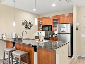 A modern kitchen with a central island, stainless steel appliances, and wooden cabinetry. - One Bedroom Condo at Bahia in Sandestin Golf and Beach Resort (Miramar Beach)