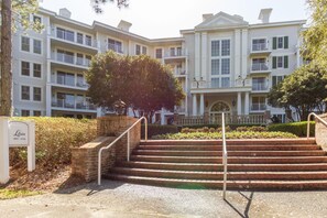 A multi-story hotel with a central entrance, a brick staircase, and a well-maintained lawn. - One Bedroom Condo at Bahia in Sandestin Golf and Beach Resort (Miramar Beach)