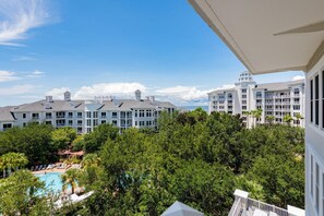 A hotel with multiple buildings, a swimming pool surrounded by trees, and a clear blue sky. - One Bedroom Condo at Bahia in Sandestin Golf and Beach Resort (Miramar Beach)