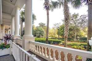 A covered outdoor area with white balustrades, palm trees, and a well-maintained garden. - One Bedroom Condo at Bahia in Sandestin Golf and Beach Resort (Miramar Beach)