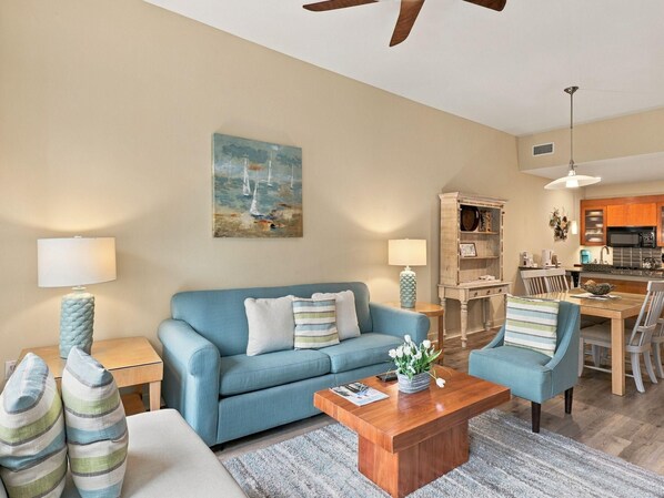 A living room with a sofa, coffee table, and a painting of sailboats. - One Bedroom Condo at Bahia in Sandestin Golf and Beach Resort (Miramar Beach)