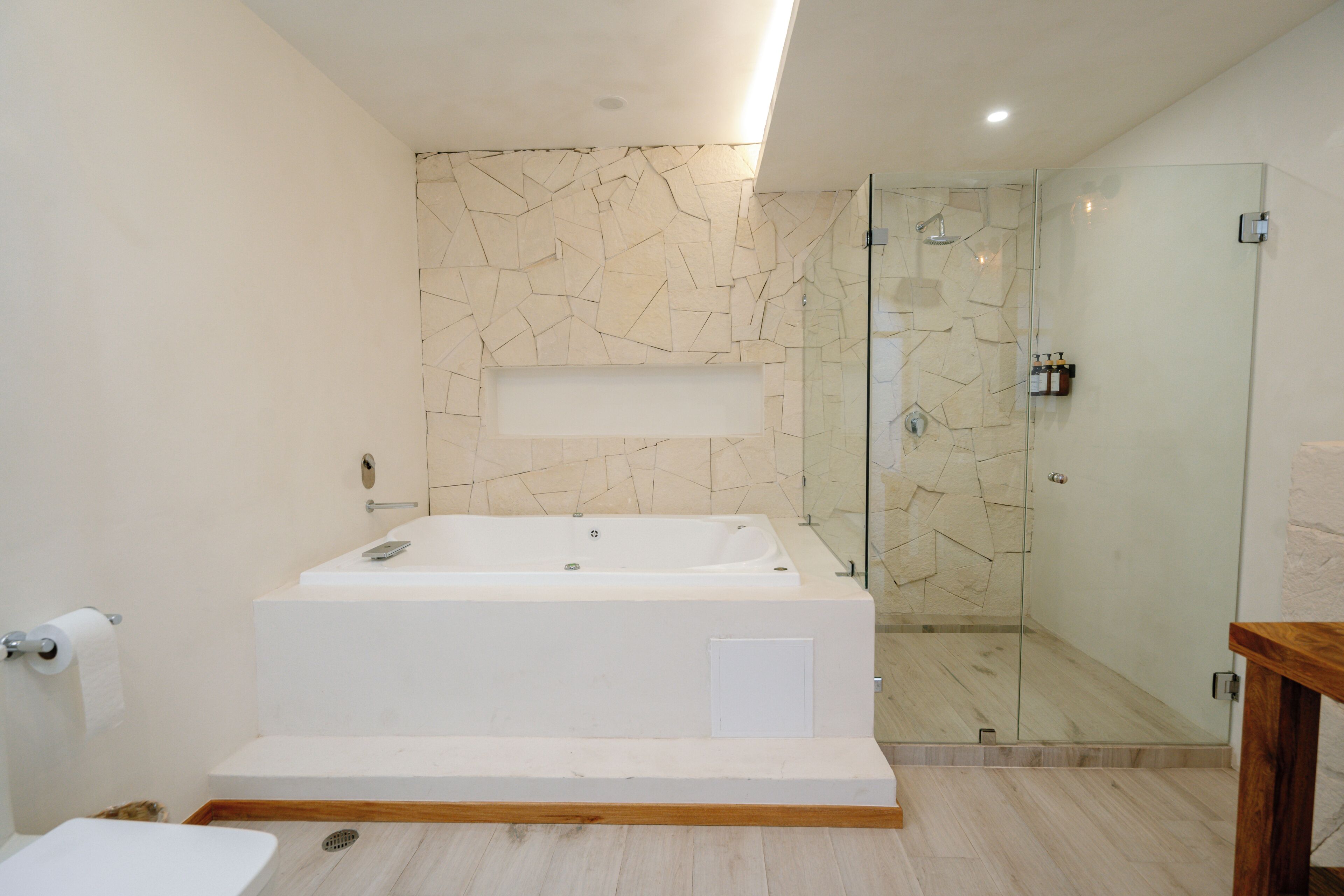 A modern bathroom with a freestanding bathtub, a glass-enclosed shower, and a wooden bench.