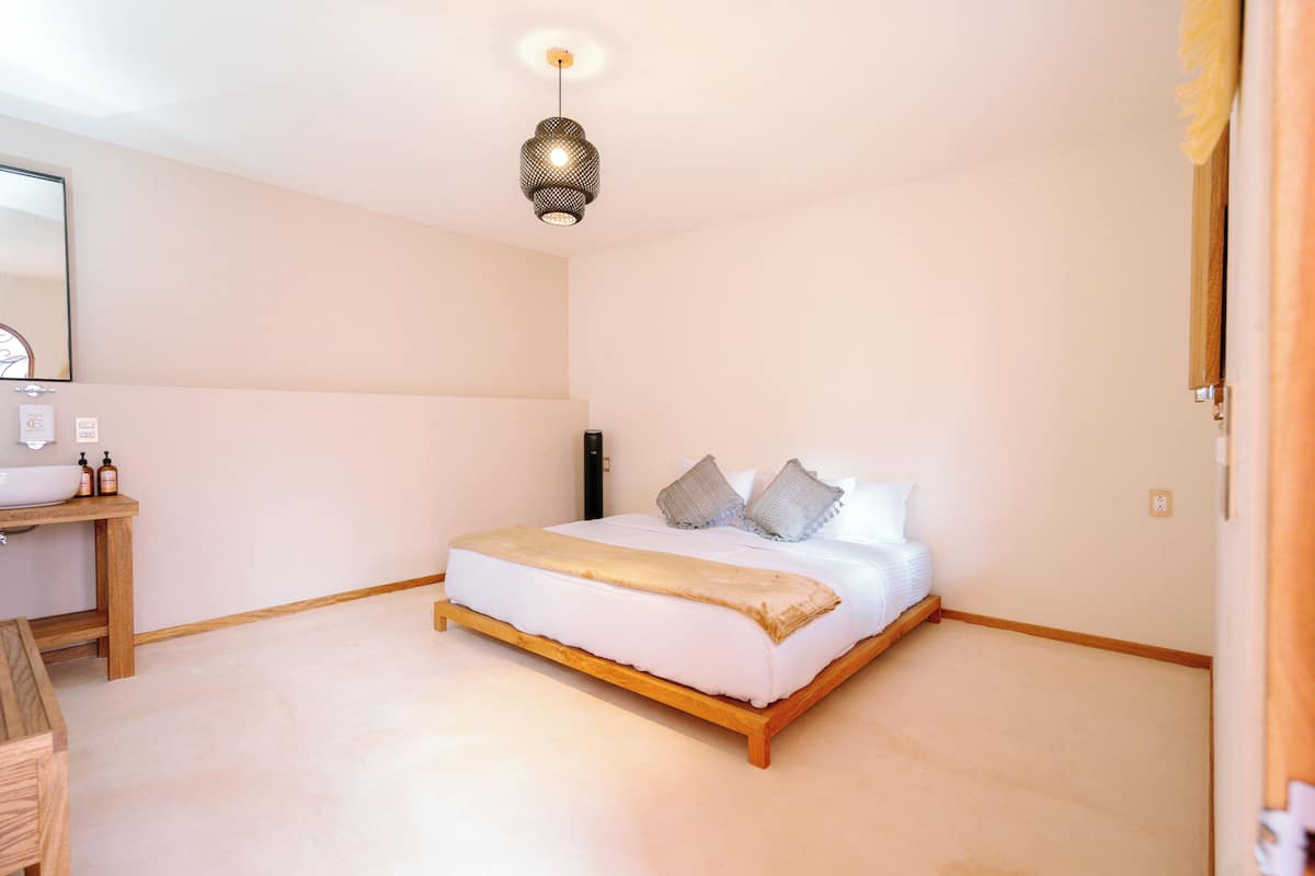 A bedroom with a wooden bed, bedside table, and a hanging light fixture.