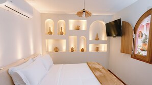 Una camera da letto con un letto, una TV a parete e vasi decorativi.