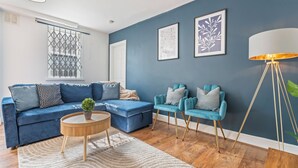 Una sala de estar con un sofá azul, una mesa de centro redonda y una lámpara de pie.