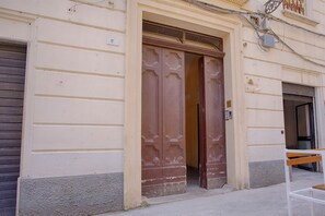 Ein Gebäude mit einer großen Holztür, einer Bank davor und einem geschlossenen Rolltor.
