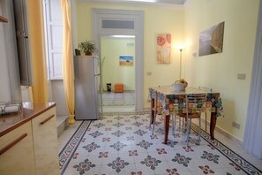 A kitchen with a patterned floor, a refrigerator, a dining table with chairs, and a door leading to another room. - Cozy 80 sq m apartment, comfortably accommodating up to 4 people, located on the first floor of a period building with NO lift. The property is located in the heart of Trapani's historic center (limited traffic zone), ideally positioned for reaching all  (Trapani)
