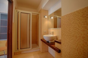 A bathroom with a glass shower enclosure, a white sink, and a tiled wall. - Cozy 80 sq m apartment, comfortably accommodating up to 4 people, located on the first floor of a period building with NO lift. The property is located in the heart of Trapani's historic center (limited traffic zone), ideally positioned for reaching all  (Trapani)