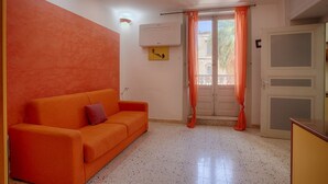Ein Zimmer mit einer Couch, einer Tür, einer Klimaanlage und einem Fenster mit Vorhängen.