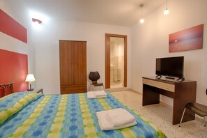 A bedroom with a bed, a desk, a television, a wardrobe, and a bathroom. - Cozy 80 sq m apartment, comfortably accommodating up to 4 people, located on the first floor of a period building with NO lift. The property is located in the heart of Trapani's historic center (limited traffic zone), ideally positioned for reaching all  (Trapani)