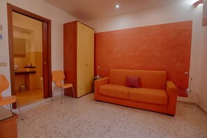 A room with a sofa, chairs, a wooden wardrobe, and a door leading to a bathroom. - Cozy 80 sq m apartment, comfortably accommodating up to 4 people, located on the first floor of a period building with NO lift. The property is located in the heart of Trapani's historic center (limited traffic zone), ideally positioned for reaching all  (Trapani)