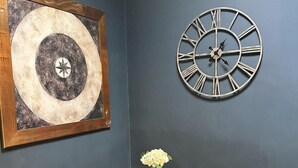 A room with a large circular artwork, a wall clock, and a small table with a vase. - Apartment Sleeps 4 With Enclosed Garden (Birmingham)