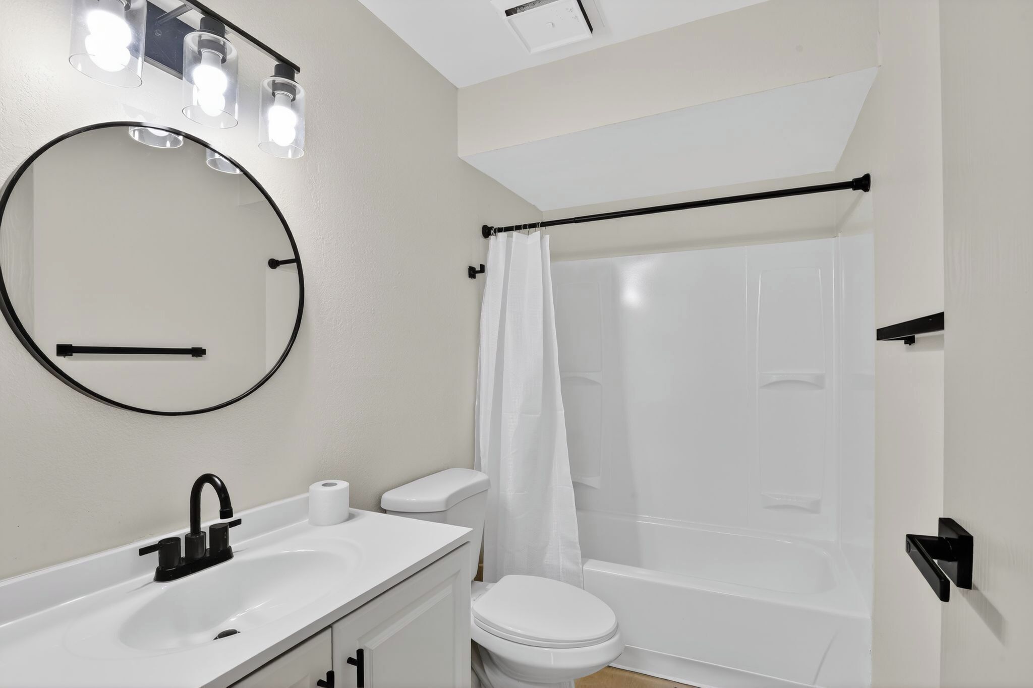 A bathroom with a white sink, toilet, and bathtub with a shower curtain.