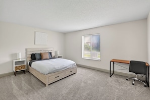 A bedroom with a bed, bedside tables, a desk, and a window. - Bright 2BR apartment near Kansas City (Lenexa)
