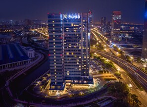 Un hotel moderno de muchas plantas, con una entrada destacada y un entorno urbano circundante con calles y otros edificios.