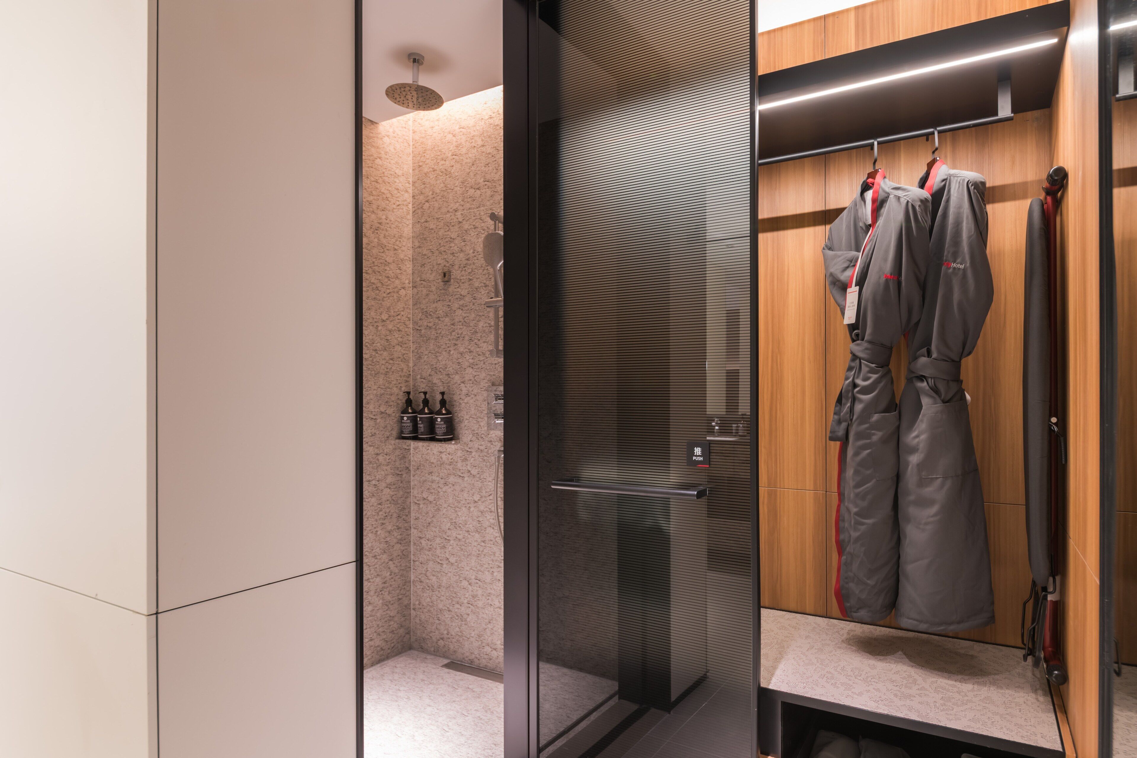 A modern bathroom with a glass shower enclosure, a wooden vanity with a towel rack, and a mirror.
