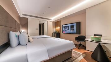 Quarto de hotel moderno com uma cama grande, uma escrivaninha e uma televisão.
