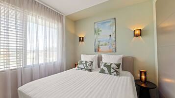 A bedroom with a bed, two bedside tables, a painting, and a window with curtains.