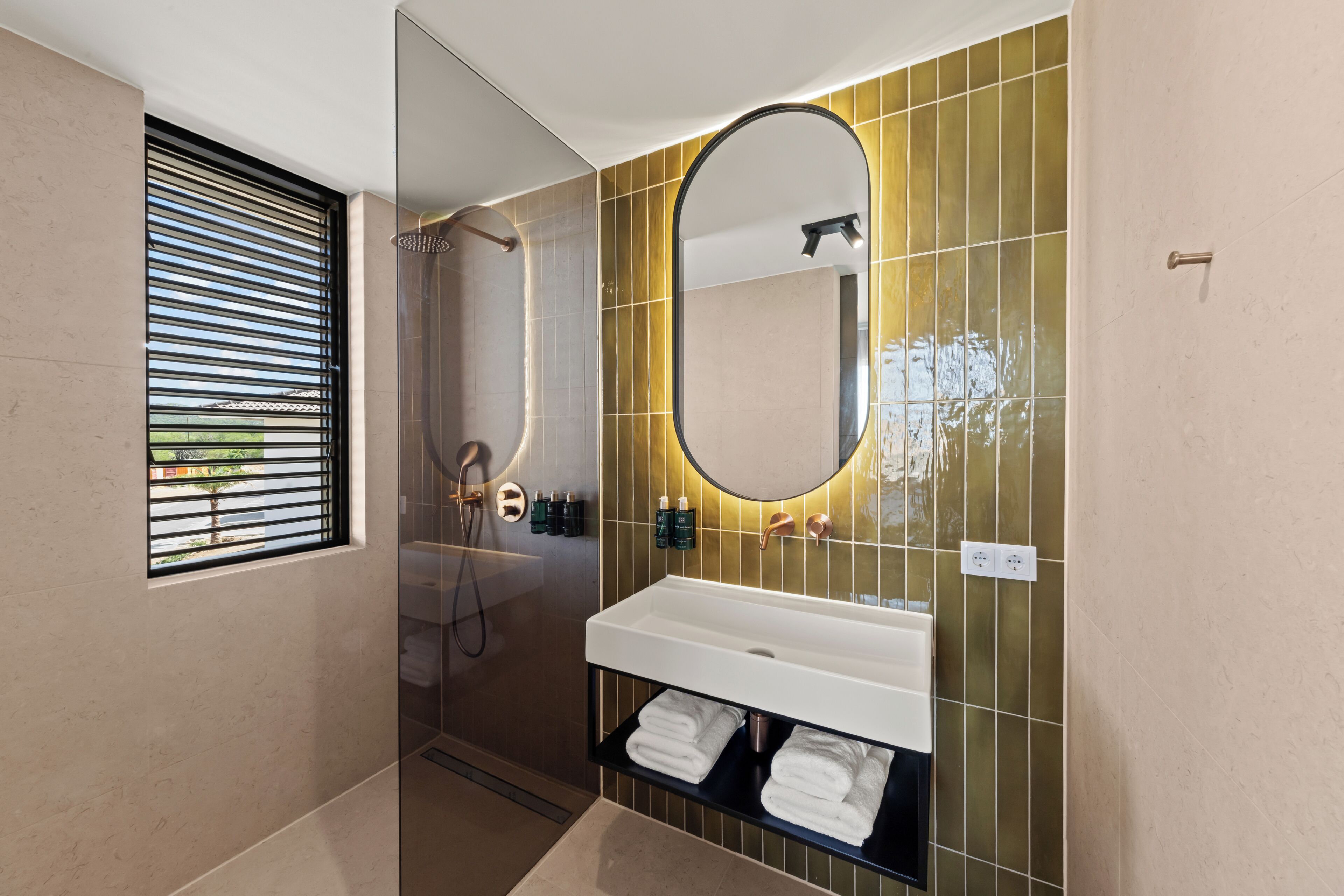 Un baño moderno con ducha, lavabo con espejo y perchero para toallas.