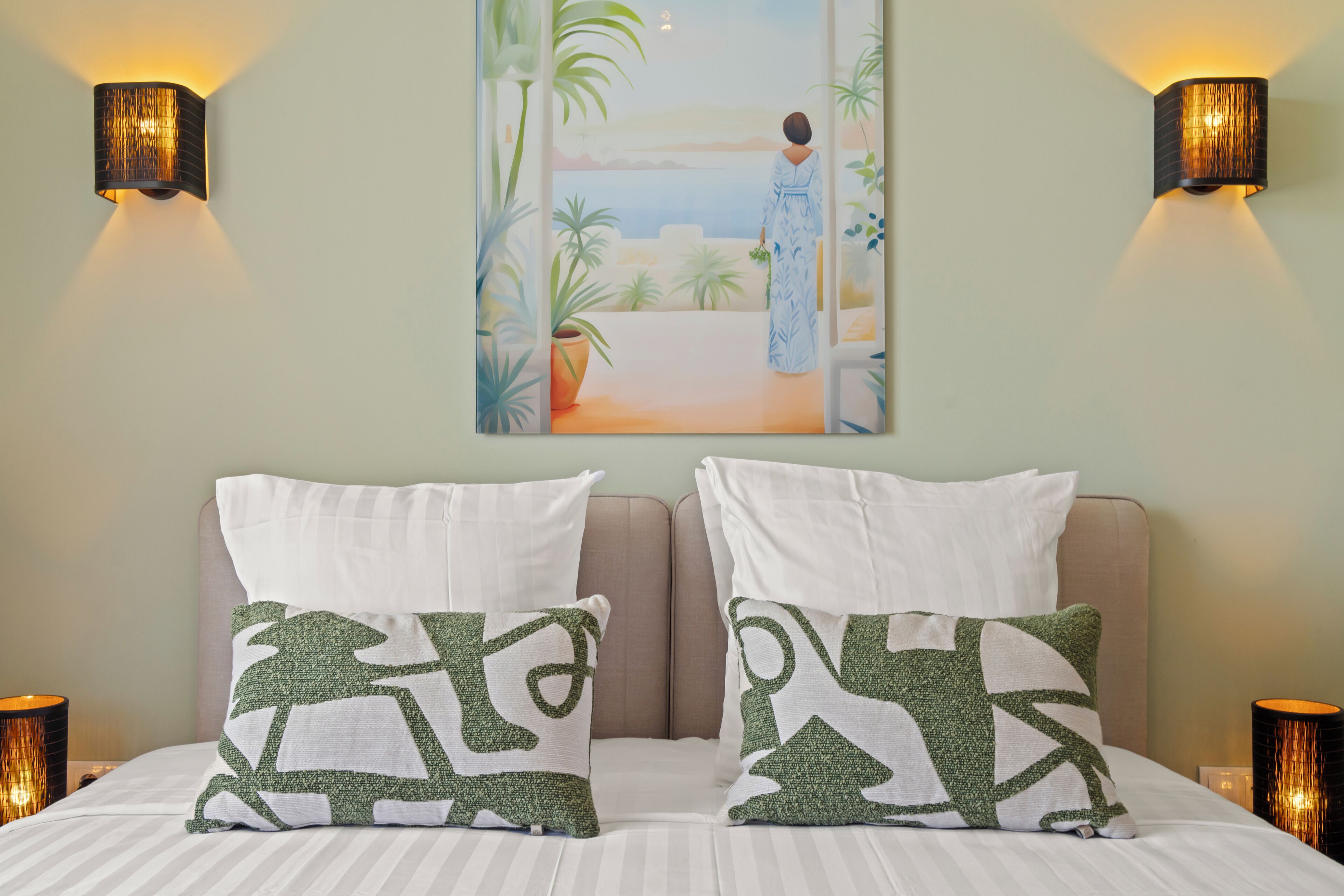 Un dormitorio con cama, dos almohadas, un cuadro y dos apliques de pared.