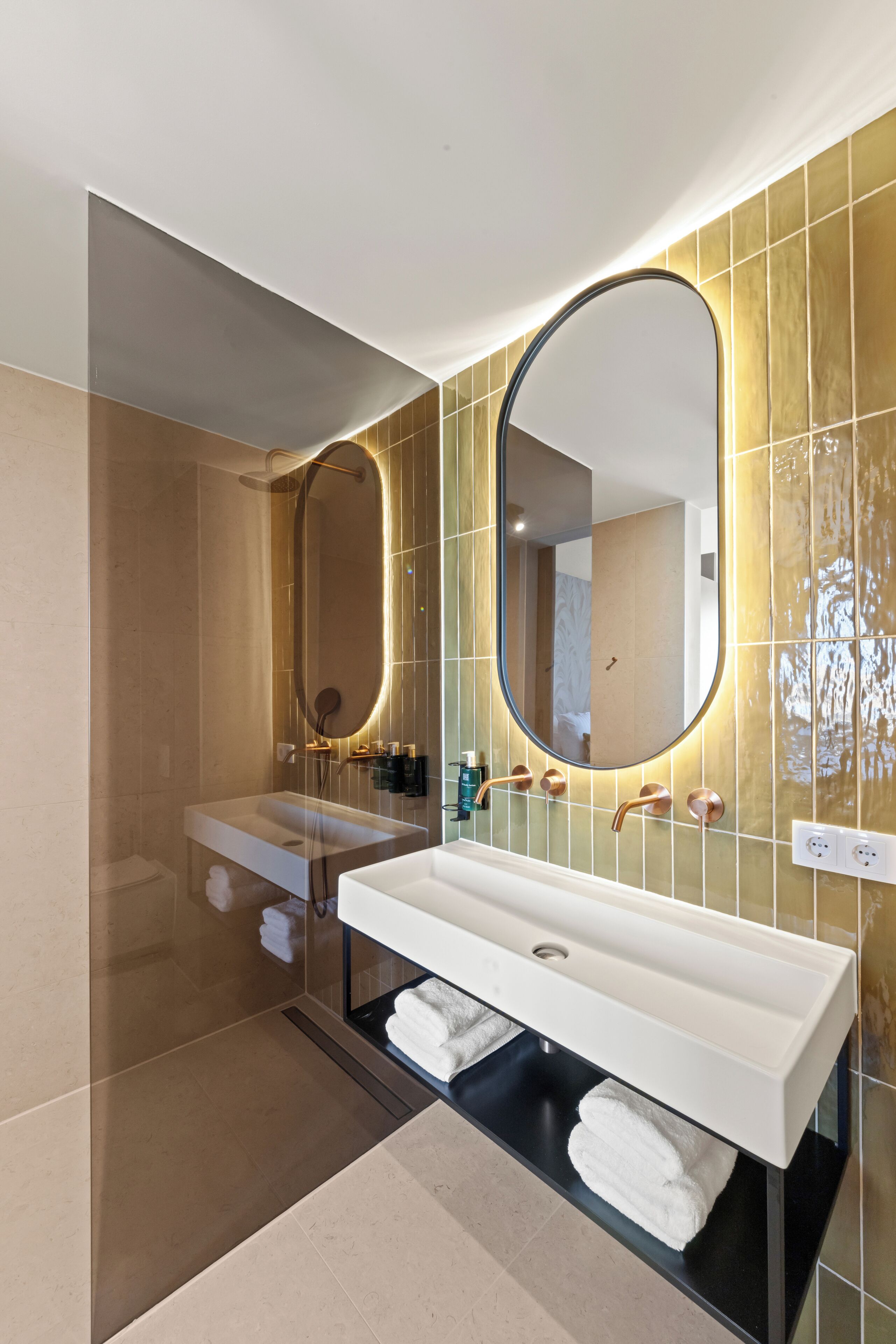A modern bathroom with a large mirror, a white sink, and a shower area.