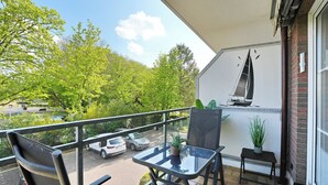 Ein Balkon mit Glastisch, Stühlen und einer Wandmalerei mit einem Segelboot.