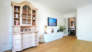 Ein Zimmer mit einem Holzkasten, einem weißen Konsolentisch und einem gerahmten Bild an der Wand.